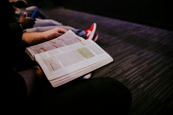 A person holds a bible with highlighted verses.