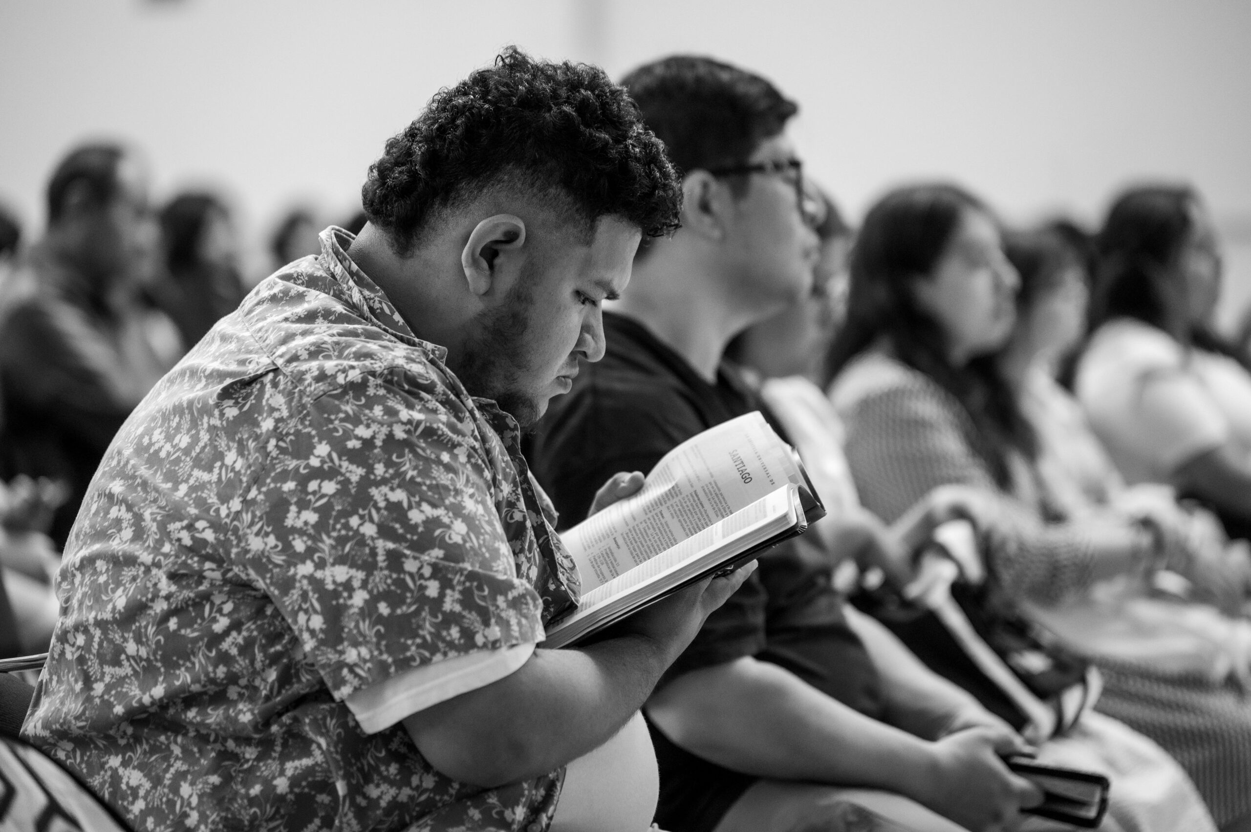 A young man reads the Bible in a group.